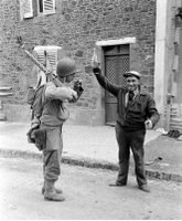 Frenchman offers a glass of wine to an American machine gunner in Coutances, France - July 1944.jpg